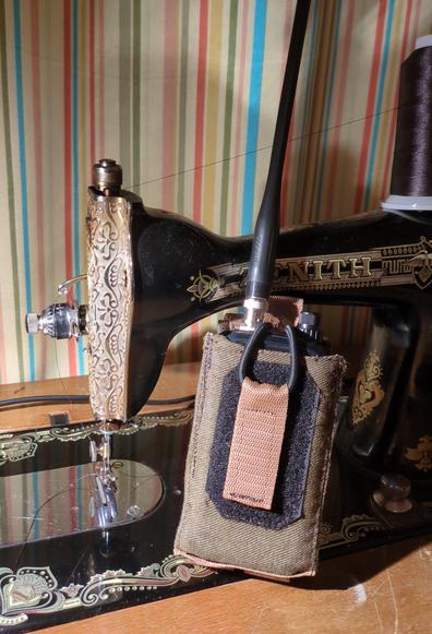 An old Zenith sewing machine holding newly sewn olive green radio bag with an kenwood th-d75 in it.