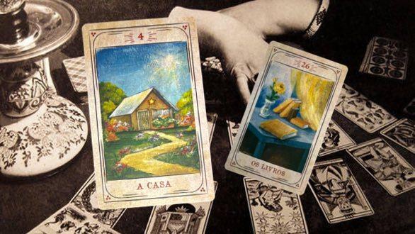 As cartas do baralho cigano “A Casa” (à frente) e “Os Livros” (atrás), sobre um fundo com motivos místicos. As cartas fotografadas tem arte gráfica de Cristina Martoni (2008), foram restauradas pelo ilustrador Lucas Teles Campos, e integram um baralho publicado originalmente por André Mantovanni/Editora Pensamento.