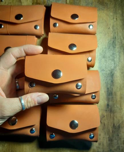 9 petits porte-monnaie en chambre à air rouge brique pâle, assemblés par des rivets, avec fermeture par rivet aimanté, dont un tenu dans ma main