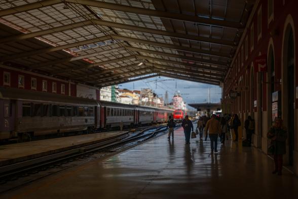 looking out from inside Santa Apolonia station on a rainy day with the distant buildings getting hit by transient sun