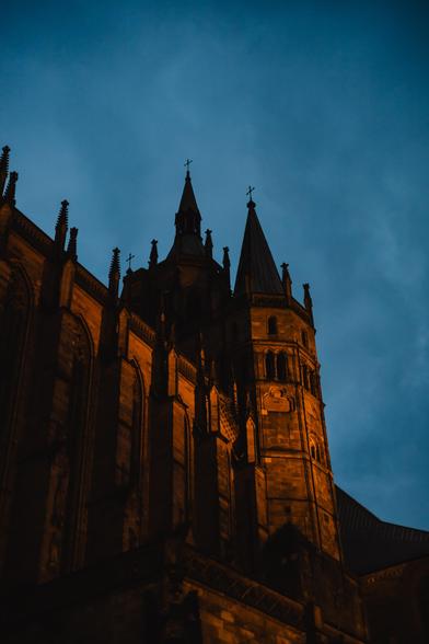 photo of the Erfurt cathedral during the blue hour. the church itself is slightly illuminated with orange light.
