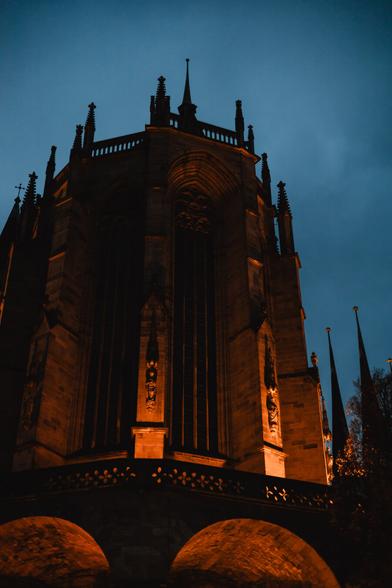 photo of the Erfurt cathedral during the blue hour. the church itself is slightly illuminated with orange light.