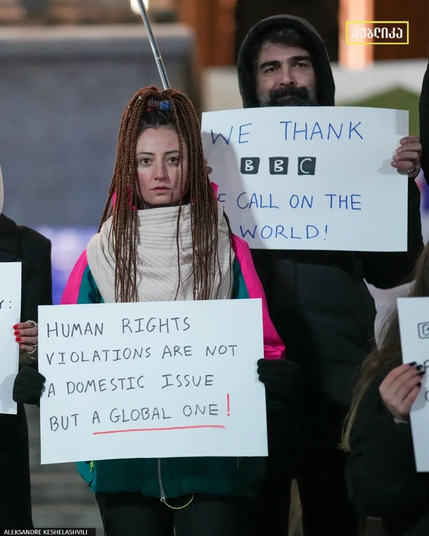 Two protesters holding signs thanking BBC for investigation exposing usage of WWI chemical weapon by "Georgian Dream" against protesters in 2024