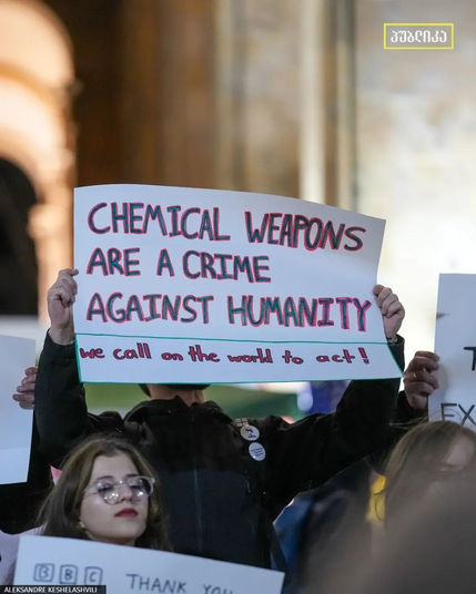 Protester holds sign with text:
CHEMICAL WEAPONS
ARE CRIME
AGAINST HUMANITY
We call the world to act!