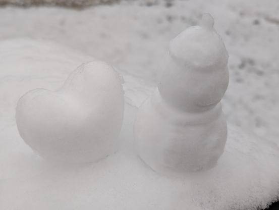 Photo of a little press-molded heart and snowman next to each other, perched atop a mailbox covered in snow.