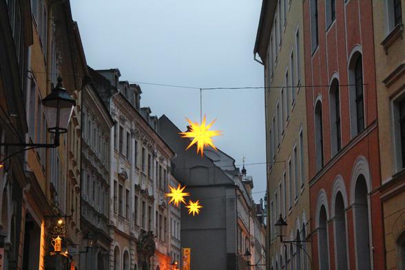 Colourful old houses in the half dark with star shaped lanterns between them.