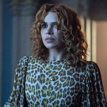 A younger woman with curly blonde hair wearing a leopard print shirt.