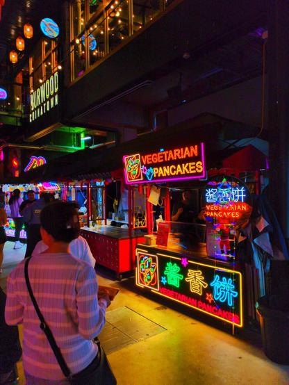 A brightly-lit night market stall selling vegetarian pancakes.