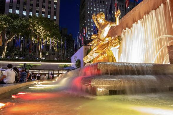 An exquisite gilded sculpture graces the heart of a bubbling fountain, enhancing the allure of the renowned Rockefeller Center in the bustling urban expanse of New York City.