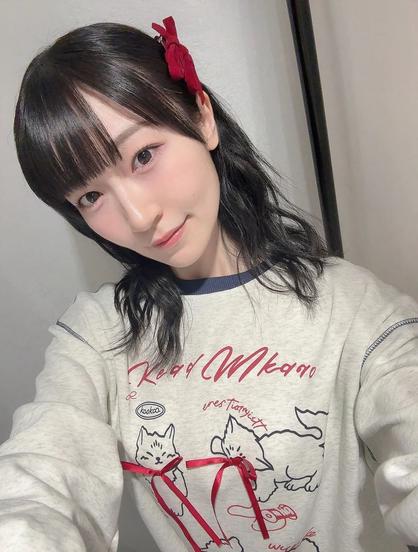 A smiling woman wearing a shirt with two kittens