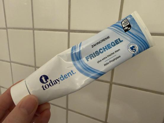 Foto einer Zahnpasta-Tube vor Badezimmer-Fliesen. Auf der Tube steht „today dent FRISCHEGEL“, zusammengeschrieben, so dass man Frische-Gel oder Frisch-Egel lesen kann …
