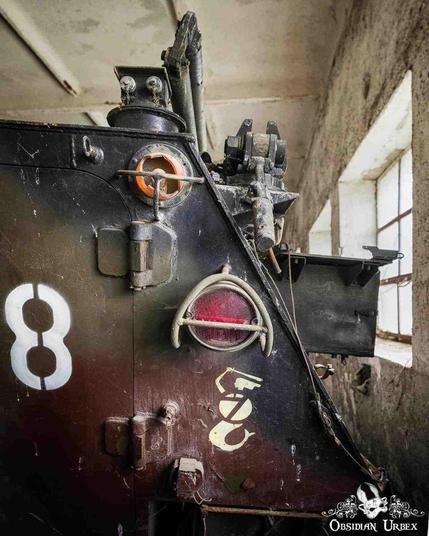 A close-up image shows the rear corner of a SKOT Armoured Personal Carrier with faded camouflage, stenciled "8", and a red light, parked inside.