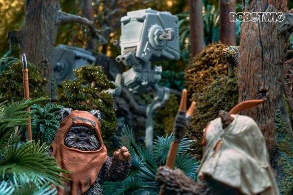 Wicket signals Paploo in the forest. AT-ST's can be seen in the background patrolling the area