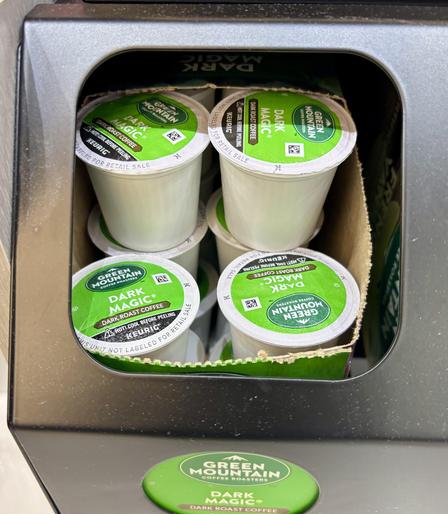 Container of coffee pods. They are labeled “Dark Magic”. Green labels, white pods.