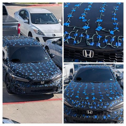 Black Honda covered in Christmas lights which are attached by squares of blue painters tape in about a 4x4-in grid