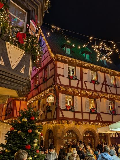 medieval buildings with golden Christmas lights, a black night sky, a Christmas tree.