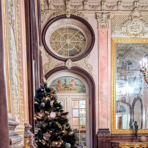 An elegant interior shot of the Palácio de Estoi, featuring a white paneled door partially obscured by a decorated Christmas tree.