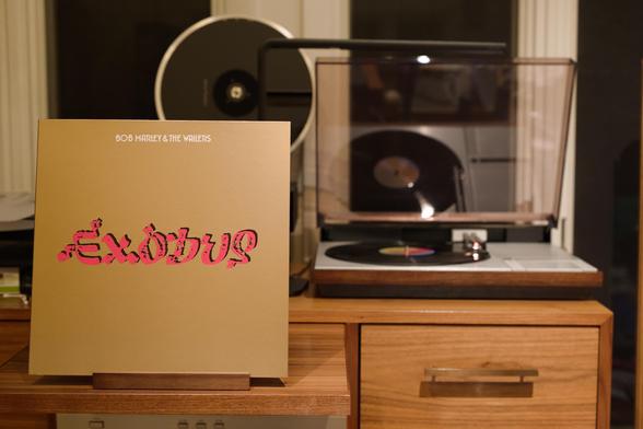 Bob Marley & The Wailers - Exodus LP cover.

A gold background, with Exodus in red, embossed, centered. Artist at the top, in white.

The black LP plays on a vintage, restored Bang & Olufsen Beogram 4000 linear-tracking turntable to the right.