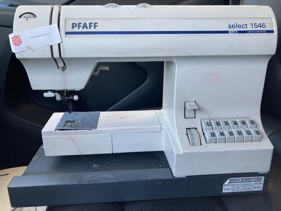The outside of a pfaff select 1546 sewing machine, from the mid-2000s. It has a panel of buttons on the right for various stitch types. Along the top are two wheels to adjust the needle. It is filthy with grime.