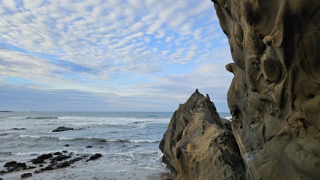 waves breaking behind sandstone rocks