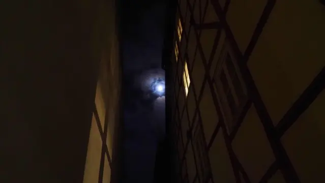 Mond an wolkigem Nachthimmel aus einer Gasse betrachtet