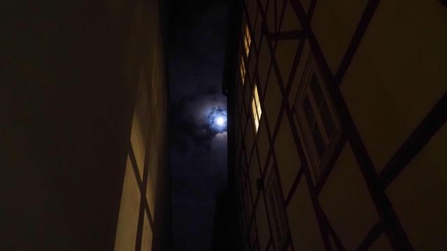 Mond an wolkigem Nachthimmel aus einer Gasse betrachtet