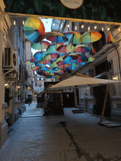 A backyard with commercial use for cafes in restaurants in Bucharest, Romania that sports very many colourful umbrellas