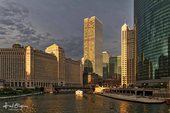 Merchandise mart in Chicago at sunset with sunlight cast over the buildings that are on the banks of the Chicago river