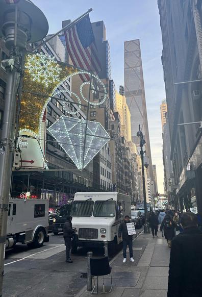 A holiday light on the side of a lamppost is seen, in the shape of a faceted gemstone. A small USA flag is on top of the lamppost, also.