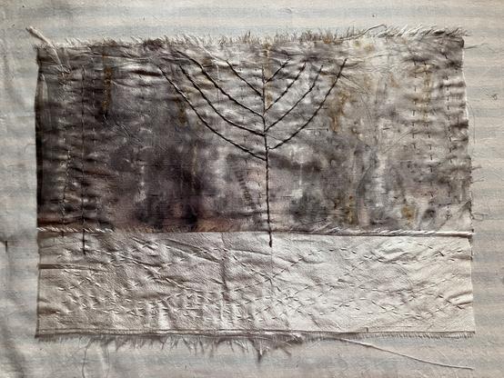 A rectangle of fabric in shades of white and gray, stitched with stylized, bare branched trees.