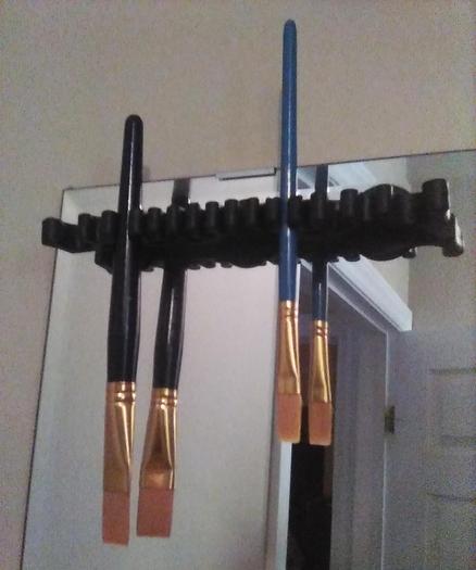 a black rubber brush-holder rack with suction cups to stick it onto a wall and rubber clips that a couple of thick-handled paintbrushes are clipped into