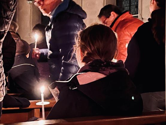 Kind mit Kerze von schräg hinten fotografiert.