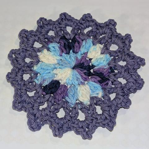 Another floral-type crochet coaster in periwinkle and purple, blue, and white multicolor. This one is made using the same colors as the previous one only, they're in opposite places.