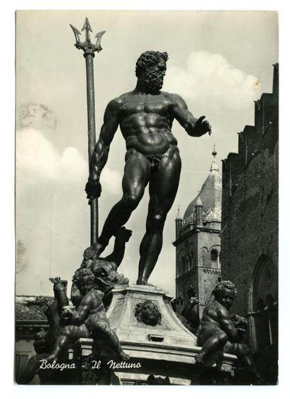 The black and white photograph displays a towering bronze statue of Neptune, the Roman god of the sea. He stands atop an elaborate pedestal with figures that appear to be cherubs or putti engaging in various activities such as playing musical instruments and holding fruit. The central figure holds aloft a trident, symbolizing his dominion over the seas.

Behind the statue is part of what appears to be a medieval cityscape, including parts of buildings and a dome-like structure that might suggest historical architecture typical of Italian cities like Bologna. In the top left corner, there's handwritten text "Bologna - Il nettuno," which translates from Italian as 'Bologna - Neptune,' indicating this statue is located in Bologna.

The image conveys an aura of antiquity and cultural significance, with attention to detail on both the sculpture itself and its surroundings hinting at a location rich in history. The weathered appearance of the photograph suggests it might be quite old, possibly dating back several decades or more.
