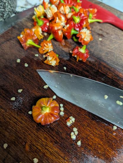 A wood cutting board covered with cut red peppers.