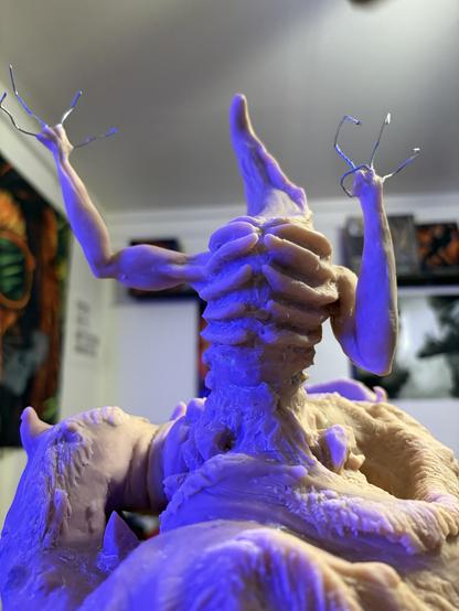 The front view of Seath with a bright blue light bounding off of his side and rib cage that is exposed. There’s a weed lion tapestry blurred in the wall behind as well.