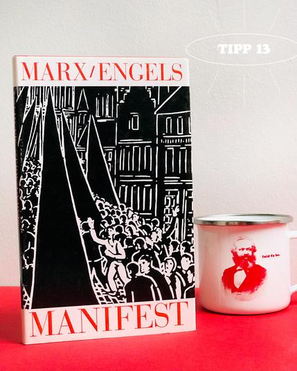 Tipp 13: »Manifest der Kommunistischen Partei« von Karl Marx und Friedrich Engels. Illustrierte Ausgabe mit elf Holzschnitten von Frans Masereel. Daneben steht unsere neue Karl Marx-Tasse, mit einem Porträt von Marx und »Told Ya So« auf der einen Seite, und der »Allgemeinen Wertform« aus »Das Kapital« auf der anderen Seite.
