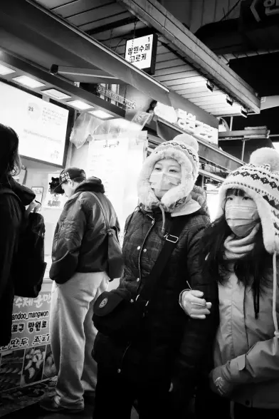 Two people walking together with hats, coats, gloves and face maasks. Holding each other.