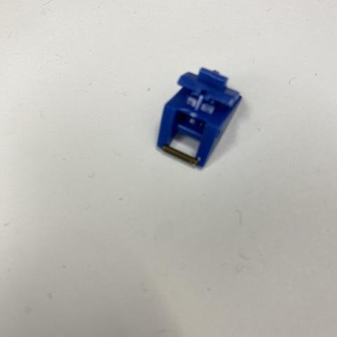 Little blue part made of plastic. Has a tiny metallic pin on one end.