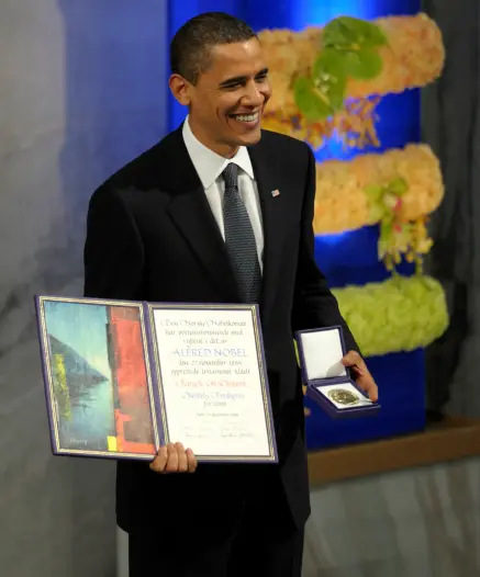 Barak Obama holding his 2009 Nobel Peace Prize.