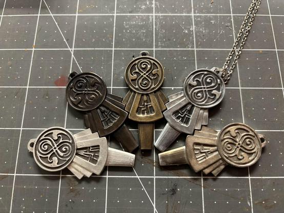 Photo of 5 small metal TARDIS keys with various patinas ranging from silvery metal to brass and dark bronze.