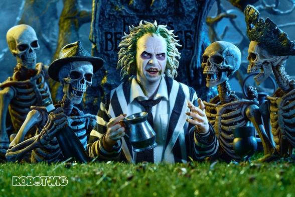 Beetlejuice stands in a grave drinking with 4 skeletons