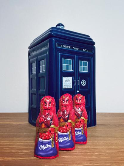 Three small chocolate demons in front of a TARDIS-shaped cookie jar.