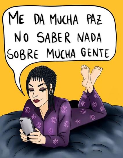 Una mujer de piel clara y cabello oscuro, con un estilo gótico o alternativo (maquillaje dramático, piercings), está recostada boca abajo sobre lo que parece ser una cama o superficie oscura. Lleva un pijama morado con estampados de pentagramas y está mirando su teléfono móvil. Sobre ella, en una burbuja de diálogo, se lee la frase: "ME DA MUCHA PAZ NO SABER NADA SOBRE MUCHA GENTE". El fondo es de color amarillo brillante y el estilo es de ilustración o caricatura cómica.