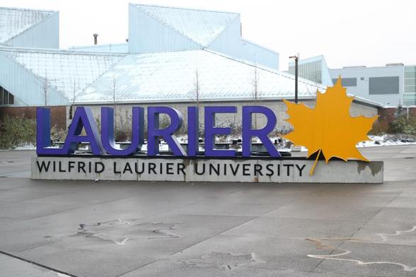 Photo taken outside of the purple, 3D "LAURIER" sign at the corner of King St. and University Ave. W.