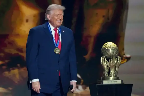 Trump smiling wearing a medal, standing next to the FIFA Peace Prize, a golden trophy of a globe being held up by severed hands.
