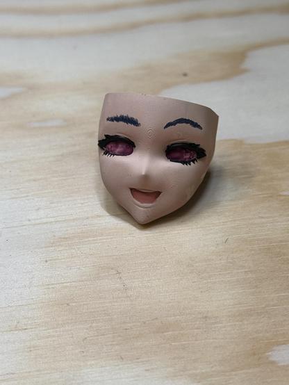 A head of a 3d printed anime figurine of a vtuber. It is in an early stage with skin, brows and lashes painted. Also the underpainting of Magos purple for the inside of the eyes.