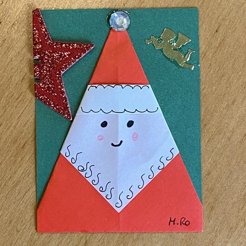 Eine grüne ATC mit einem aus rotem und weißen Papier gefalteten Nikolaus-Portrait.
Verziert mit einem aufgeklebten roten Stern und einem goldenen Engel.