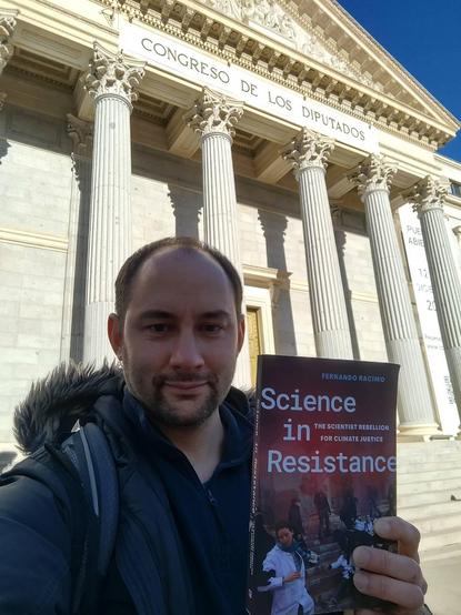 Photo of me holding my book in front of the Spanish Congress in Madrid