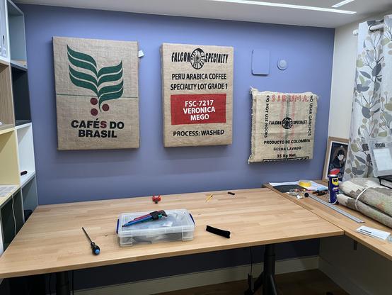 A home office with three coffee sacks used as acoustic paneling on the wall.